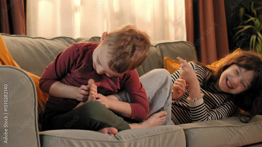 Happy children tickling and laughing on sofa