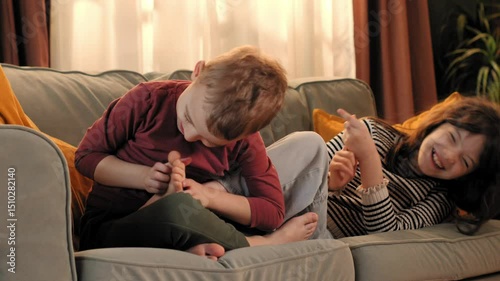 Happy children tickling and laughing on sofa