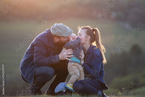 Happy family with a little son enjoying spring sunset outdoor.