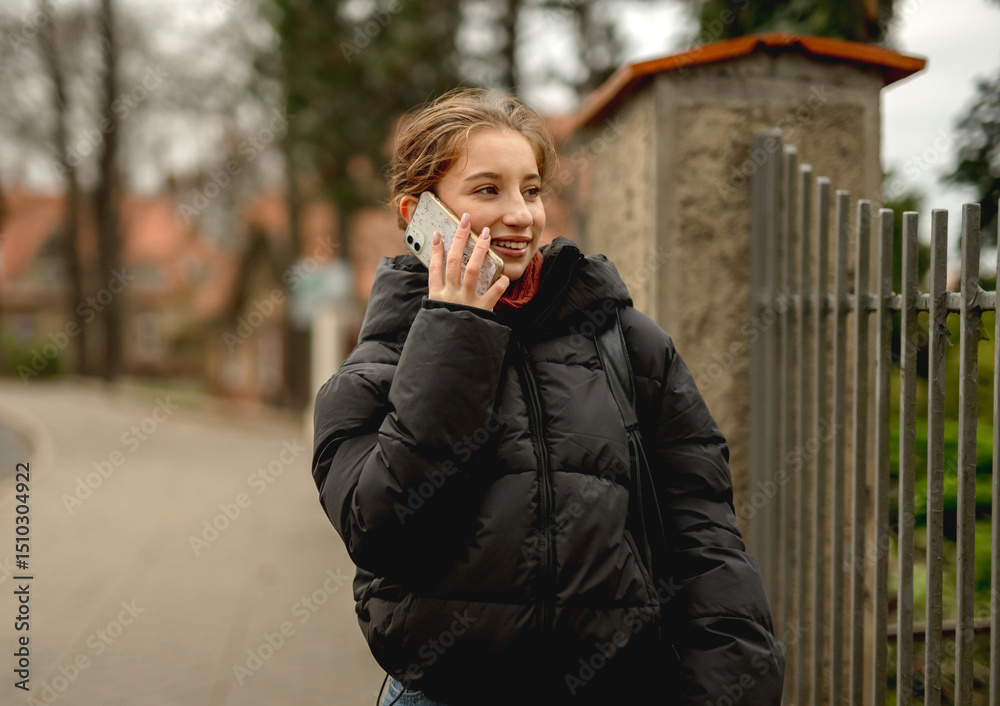 Fototapeta premium Happy Girl Talking On The Phone Against A Blurred Street Background