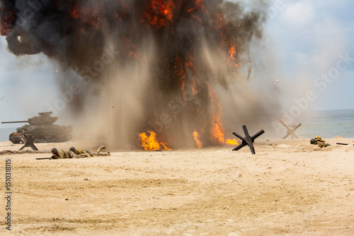 World War II historical reconstruction. Battlefield. Explosions, a tank, and American soldiers on the beach. Smok and dust.