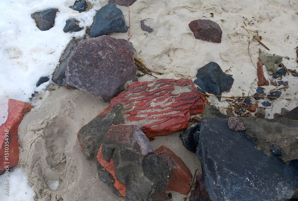 Obraz premium Varied Colored Rocks on Sandy Beach with Snow Patches in Winter