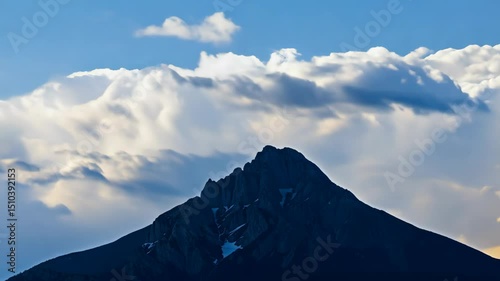 Majestic mountain silhouette against a soft, pale blue sky with scattered clouds