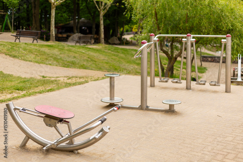 Fototapeta Naklejka Na Ścianę i Meble -  Various outdoor fitness machines are set up in a serene community park, providing a space for exercise and wellness