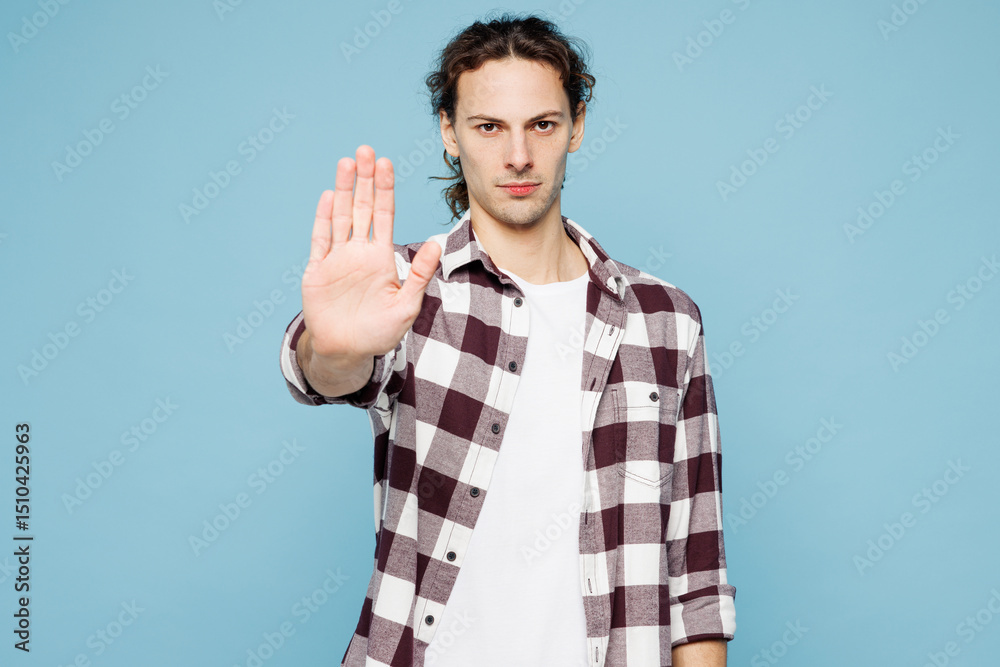 Naklejka premium Young sad strict man he wear purple checkered shirt casual clothes showing stop gesture with palm looking camera isolated on plain pastel light blue cyan background studio portrait. Lifestyle concept.