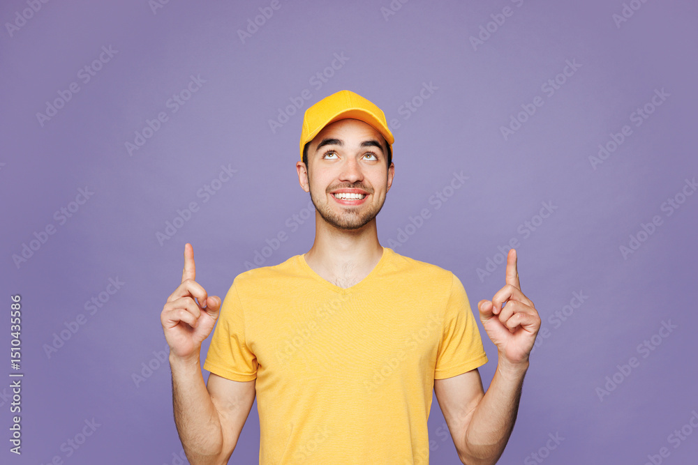 Professional delivery guy employee man wear yellow cap t-shirt uniform workwear work as dealer courier point index finger overhead on area isolated on plain pastel purple background. Service concept. Professional delivery guy employee man wear yellow cap t-shirt uniform workwear work as dealer courier point index finger overhead on area isolated on plain pastel purple background. Service concept.