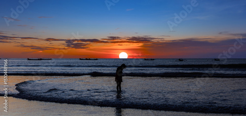 Beautiful colourful sunset on Kuta Beach on the island of Bali blue purple orange skies with turquoise blue waters and silhouette of people on the sandy beach the land of gods Bali Island Indonesia 