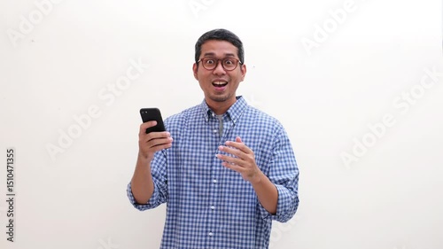 Adult Asian man looking at his mobile phone then showing joyful expression