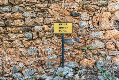 Close-up of a stone wall at Alanya Castle, Turkey, featuring a yellow sign indicating the location of the 