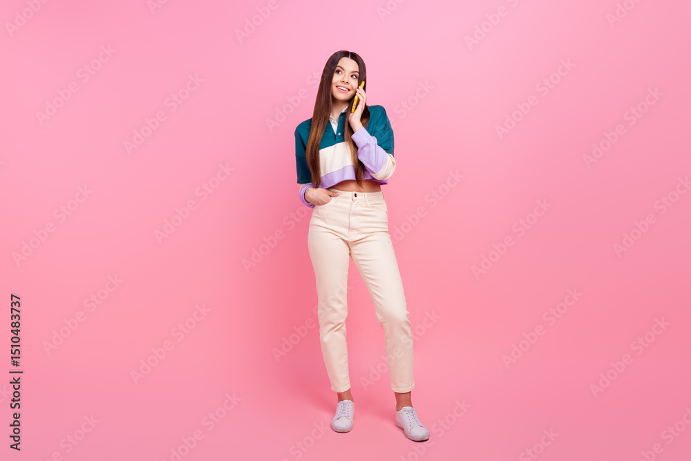 Charming Young woman in stylish casual outfit talking on smartphone against pink background Charming Young woman in stylish casual outfit talking on smartphone against pink background