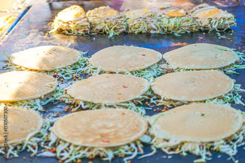 cabbage-filled pancakes on a teppan grill, a popular Japanese street food scene full of texture, flavor, and energetic preparation.