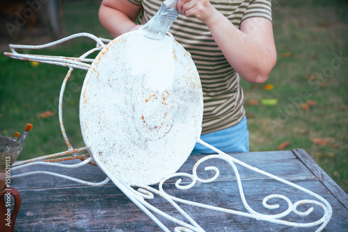 Painting an wrought iron chair outdoors, an eco-friendly re-use business.