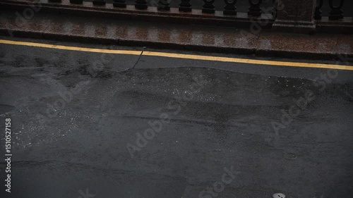 Tranquil view of deserted empty street in city during rainfall. The wet asphalt road surface reflects the surroundings with puddles on embankment. Copy space. Urban background. Bad weather theme.