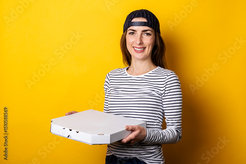 smiling young woman pizza delivery man holding package with hot fresh pizza on yellow background