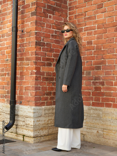 Woman in stylish coat enjoys sunny day while walking in urban setting