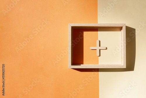 Abstract banner with a plus sign in a wooden frame on an orange-yellow background.