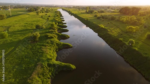 Kayakers Paddling on River at Sunset – Aerial 4K Footage of kayakers paddling peacefully on a scenic river during sunset. Surrounded by lush trees and glowing golden hour light, this tranquil outdoor 