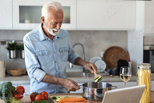 Photos Happy senior man having fun cooking at home