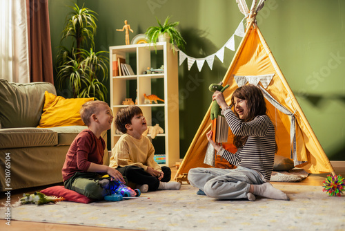 фотографія Girl playing puppet show for brothers in living room