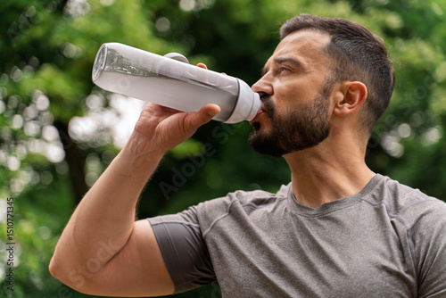 Clouse up shot Handsome bearded athlete in early forties drinking energy drink, electrolytes 