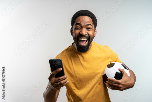 Foto Handsome happy excited African man celebrating in euphoria mood after winning a bet, holding a smartphone in hand, isolated studio background