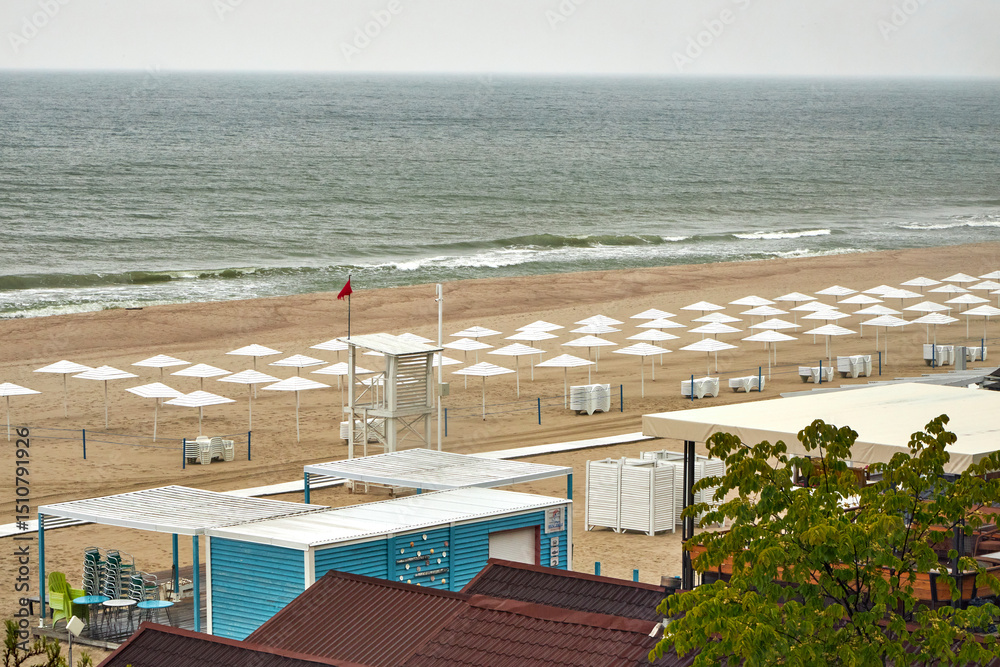 Fototapeta premium Top view of a Baltic Sea beach with white umbrellas on a cloudy day