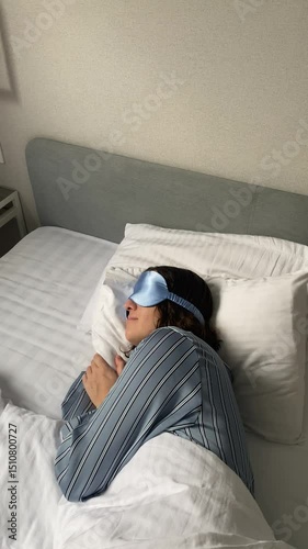 young woman sleeping in bed wearing a sleep mask