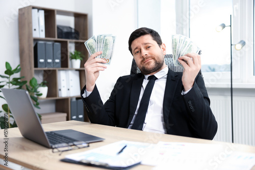 Fotografija Greedy banker with dollar banknotes at table in office