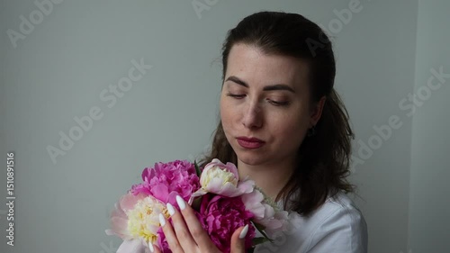 The girl sniffs a bouquet of peonies and looks into the distance. Bouquet of flowers