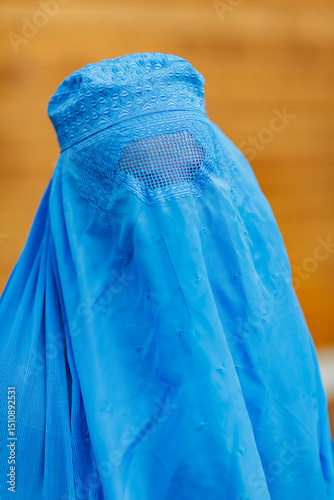 Portrait of an afghan woman wearing blue burqa, also called burka, hijab, niqab or chadri, with eyes behind the fabric grid, Kabul, Afghanistan