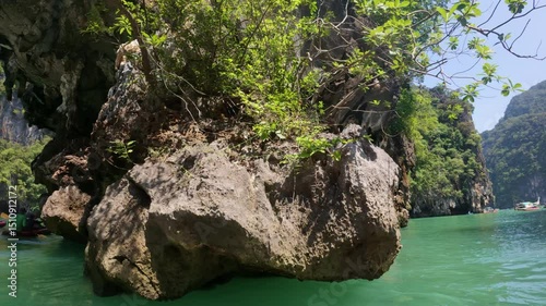 A scenic view from a boat in Honk İsland , Thailand ,  featuring clear turquoise waters and rocky cliffs under the warm sunlight.