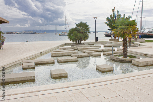 seafront in Split, Croatia. Fountain and palm trees on the shore of the Adriatic Sea.