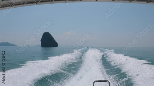 A boat moving quickly on clear waters near Phuket with frothy waves and a distant island in the background.