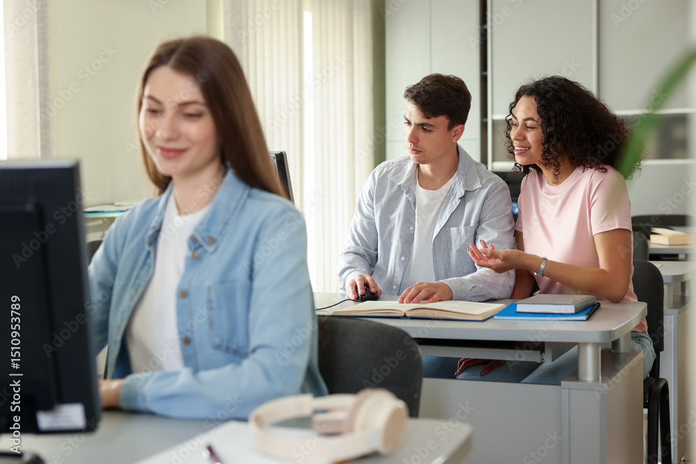 Fototapeta premium People studying at desks in public library, selective focus