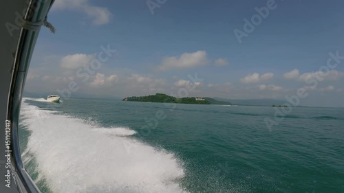 A boat moving quickly on clear waters near Phuket with frothy waves and a distant island in the background.