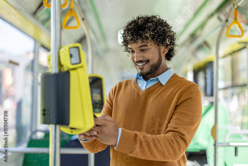 A man happily uses the electronic fare machine while riding the bus for his daily commute.