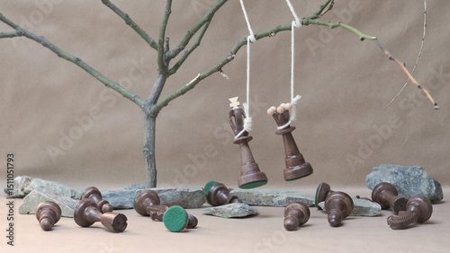 chess pieces black king and queen hanging on noose among defeated black chess pieces photo