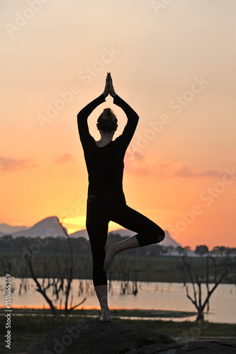Young woman practising yoga posture by the Senanayake Samudraya Lake at sunset, Gal Oya National Park, Sri Lanka, Indian subcontinent, South Asia