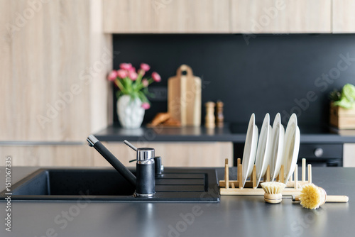Modern kitchen sink design on black countertop with stylish accessories