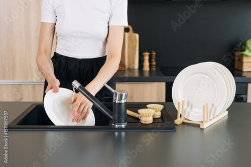 Washing dishes in a modern kitchen with a sleek black countertop setup