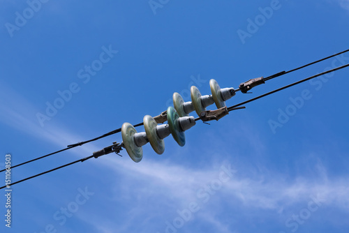 Insulators in overhead power lines against blue sky