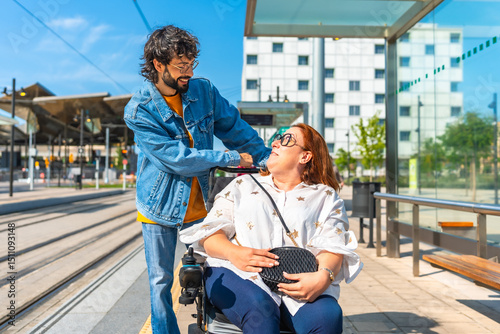 фотографія Young man assisting smiling woman in wheelchair at tram stop