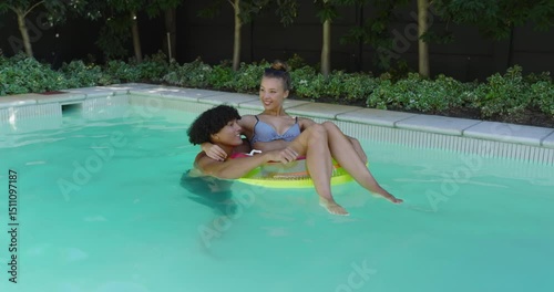 Relaxing in pool, joyful diverse couple floating on inflatable ring, enjoying summer day, copy space