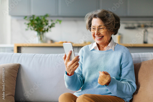 Obraz na plátně Happy elderly woman using smartphone at home, making video call, consulting doct