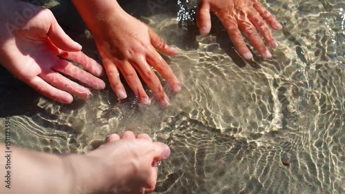 Mother and child washing hands in clear mountain river