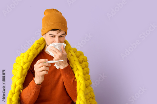 Ill young man with thermome...