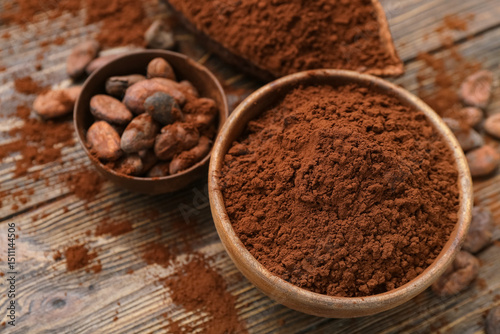 Bowls with cocoa powder and beans on wooden background