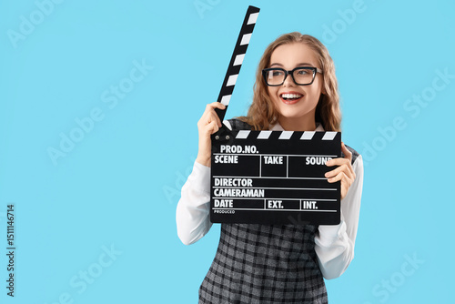Obraz na plátně Beautiful actress with movie clapper on blue background