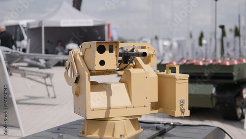 An unmanned ground vehicle outfitted with a precision weapon system is showcased at a defense technology exhibition, surrounded by military vehicles and equipment.