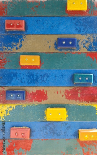 Parede rustica de tabuas coloridas com alguns blocos de madeira coloridos pregados. 